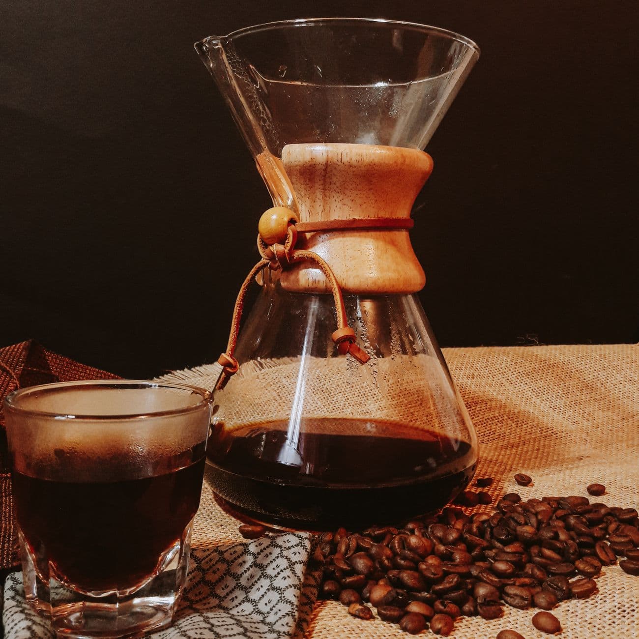 Chemex 手沖壺與一杯黑咖啡，旁邊散落咖啡豆